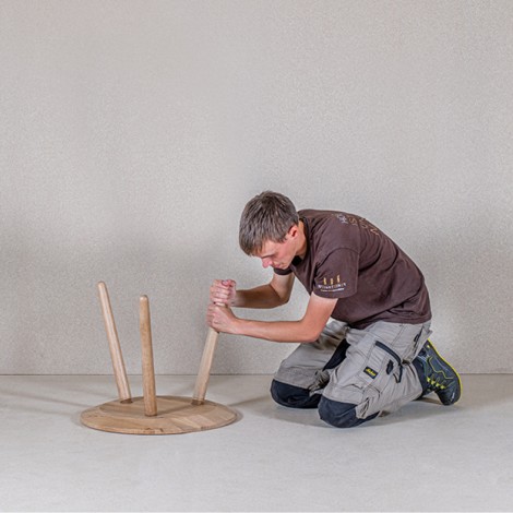 Mitarbeiter der Tischlerei Weissteiner beim anschrauben der Holzstützen in die runde Tischplatte