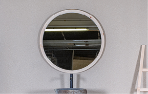 Ein runder Spiegel mit Rahmen aus heimischem Holz und eine Holzleiter.