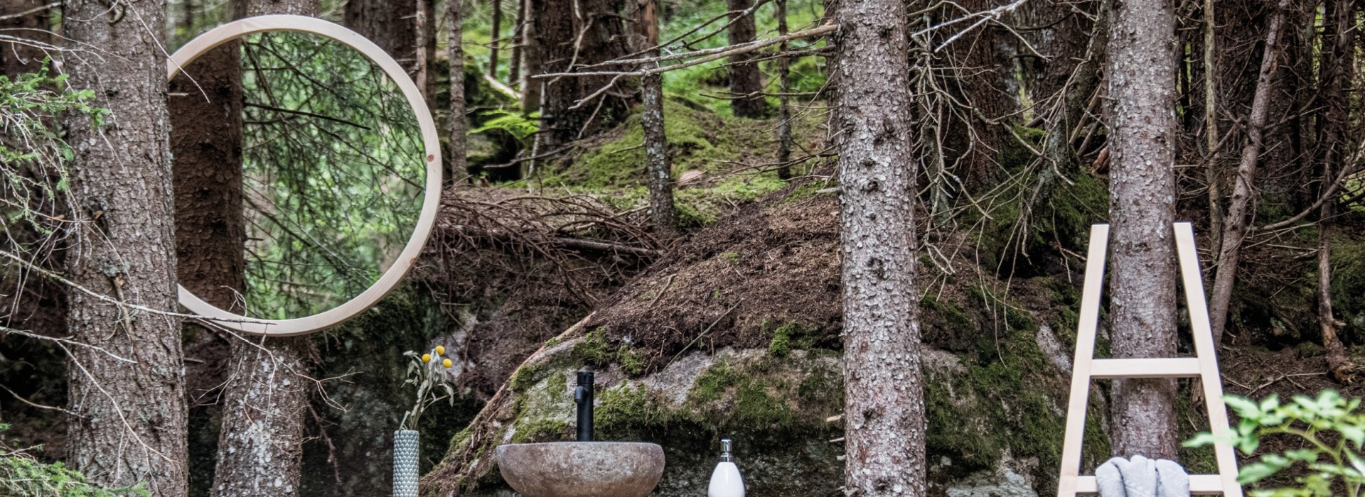 Runder Badezimmerspiegel mit Holzrahmen, hölzerner Waschtisch und Holzleiter im Wald