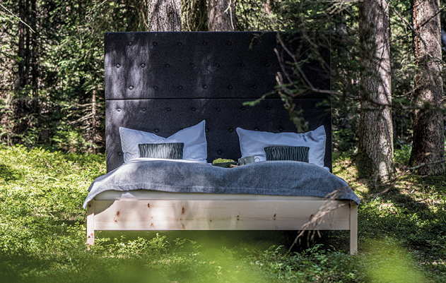 Stabiles Holzbett mit gepolsterter Rückenlehne zwischen Bäumen