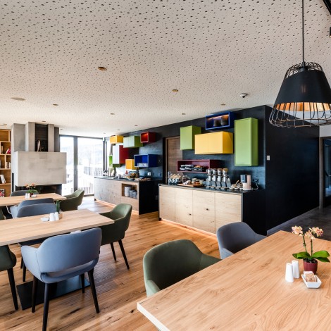 Breakfast room with wooden floor, tables, chairs and shelves made of local natural wood