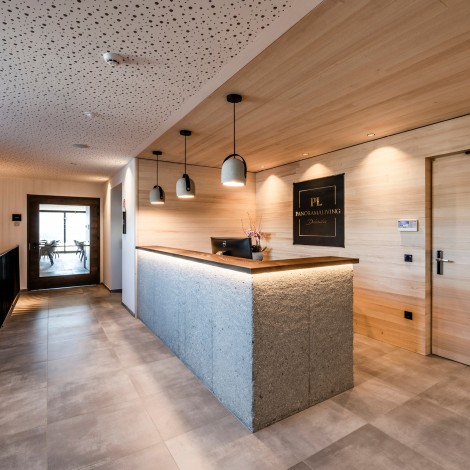 Reception area of a hotel with counter top, door and walls in light wood